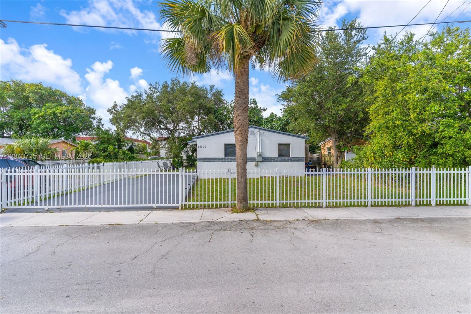 A single-story house with a white fence and a palm tree in the front yard — 15100 NE 14th Ct, North Miami Beach FL 33162, NORTH MIAMI BEACH, FL