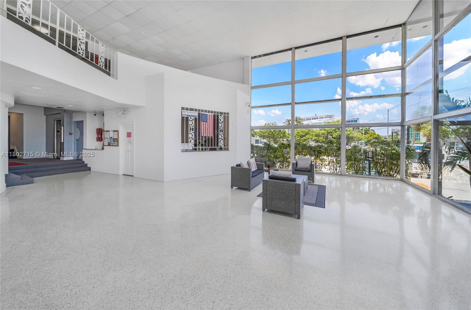 A spacious lobby features white terrazzo floors, high ceilings, and floor-to-ceiling windows — 6484 Indian Creek Dr # 202, Miami Beach FL 33141, MIAMI BEACH, FL