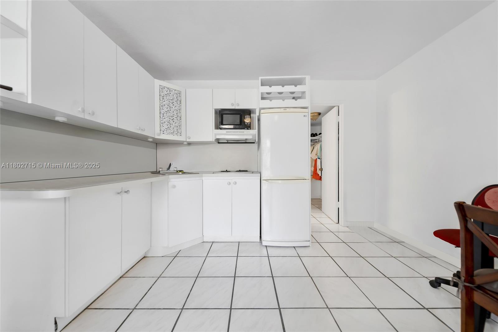 A white kitchen features white cabinets, a refrigerator, and tiled flooring — 6484 Indian Creek Dr # 202, Miami Beach FL 33141, MIAMI BEACH, FL