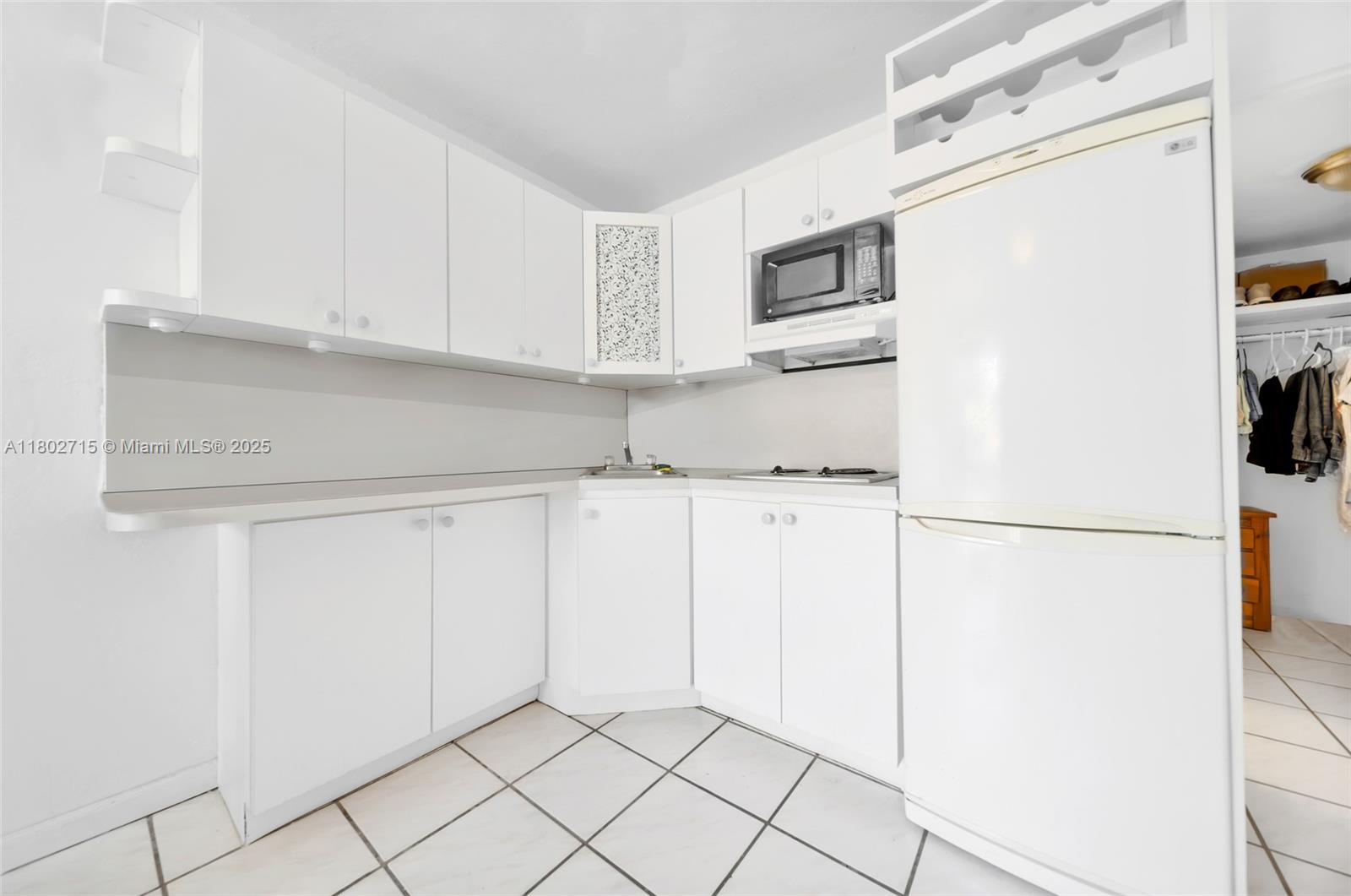 A small kitchen features white cabinets, white appliances, and white tile flooring — 6484 Indian Creek Dr # 202, Miami Beach FL 33141, MIAMI BEACH, FL