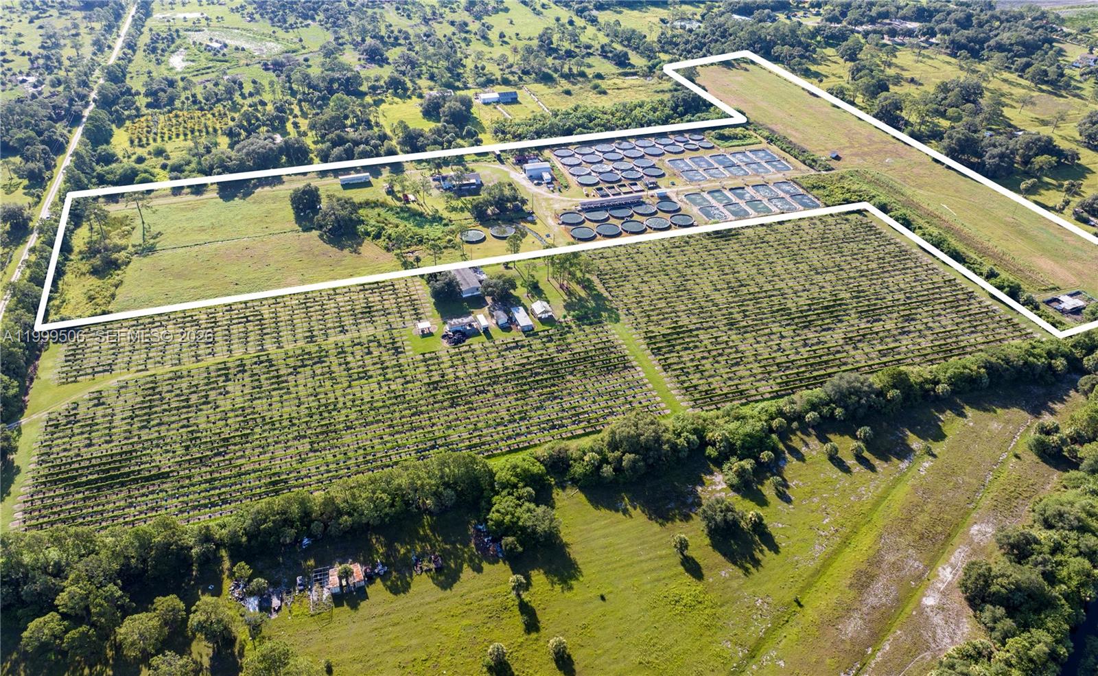 An aerial view shows a large rural property featuring agricultural fields and circular aquaculture tanks — 14759 Center Ave, Clewiston FL 33440, CLEWISTON, FL