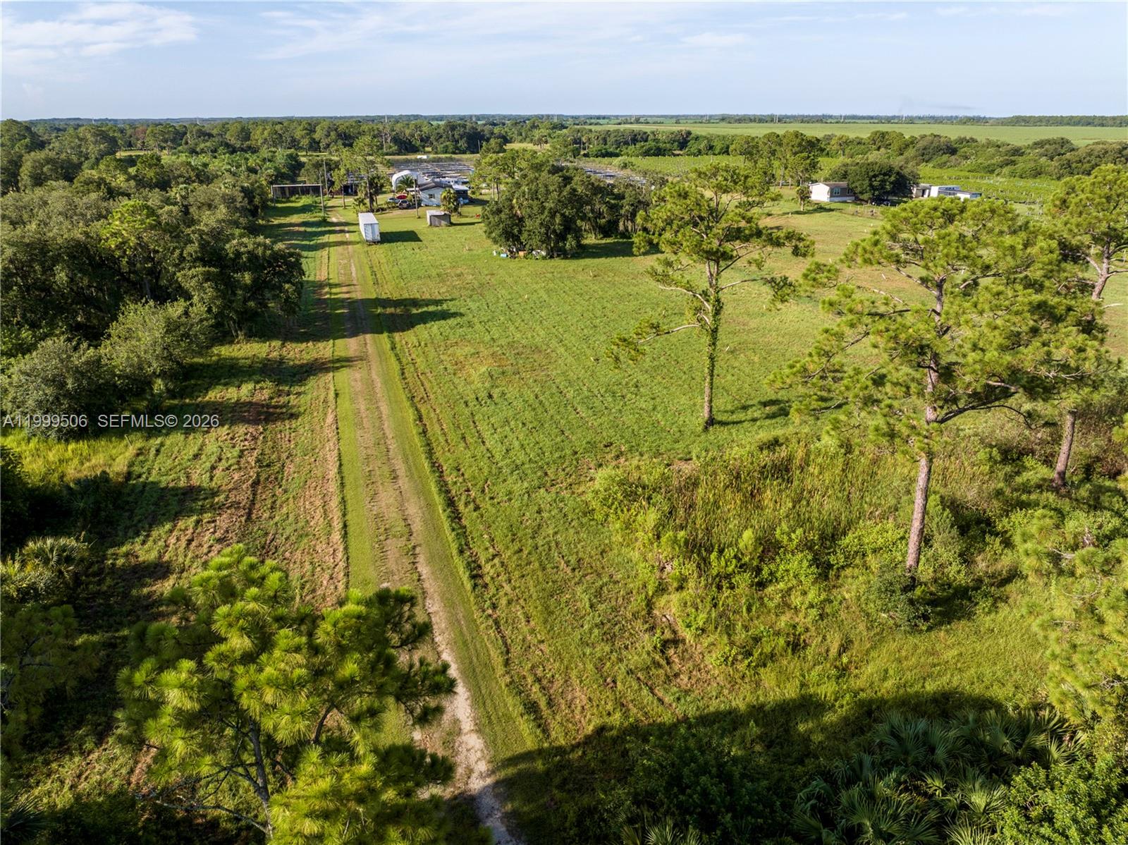 An aerial view shows a dirt path running through a grassy field with scattered trees — 14759 Center Ave, Clewiston FL 33440, CLEWISTON, FL