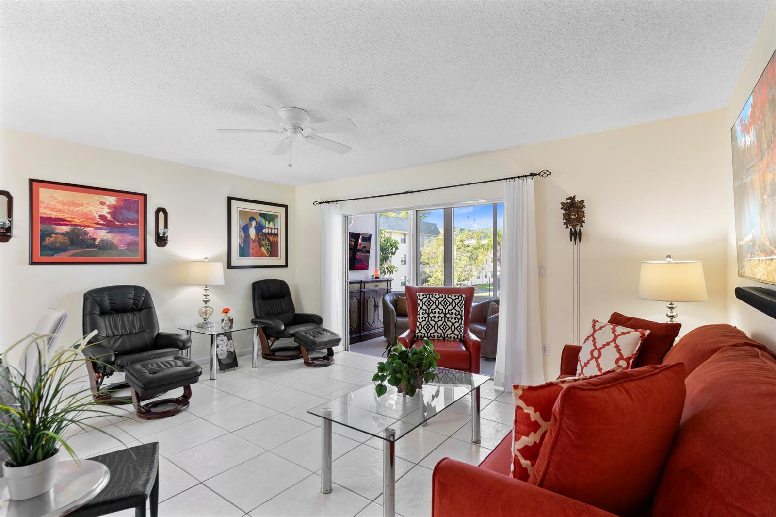 A living room features white tile floors, a red sofa, two black recliners, and sliding doors — 5180 E Sabal Palm Boulevard # 234, Tamarac FL 33319, TAMARAC, FL