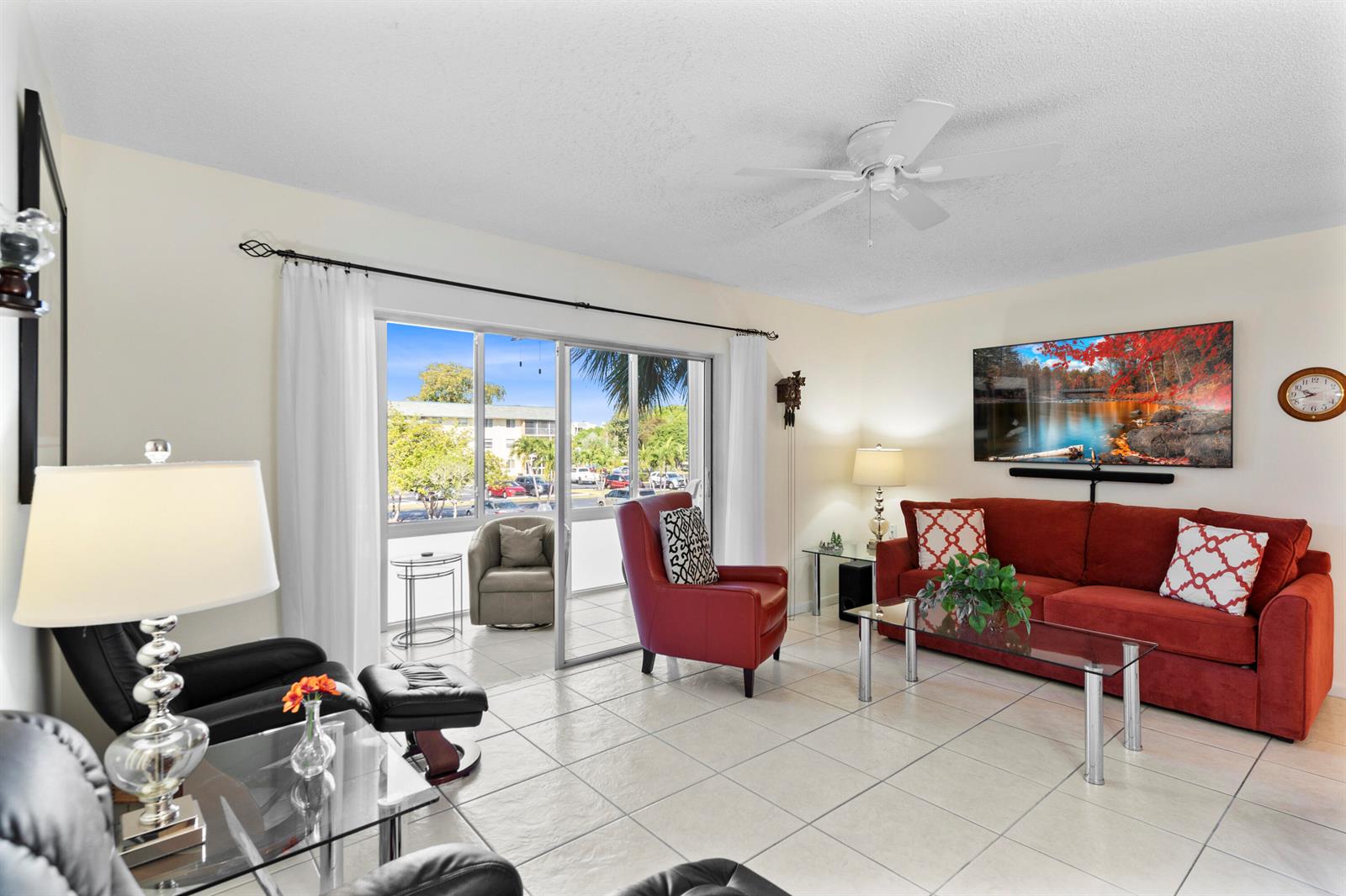 A living room features tile floors, a red sofa, a red armchair, and sliding glass doors — 5180 E Sabal Palm Boulevard # 234, Tamarac FL 33319, TAMARAC, FL