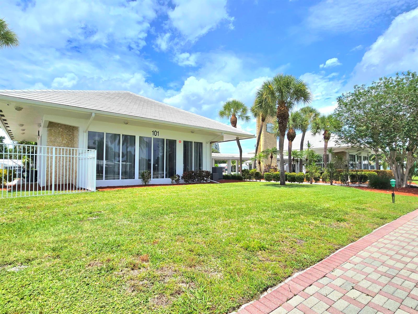 A white building with a tiled roof and large windows sits behind a green lawn — 2501 W Golf Boulevard # 127, Pompano Beach FL 33064, POMPANO BEACH, FL