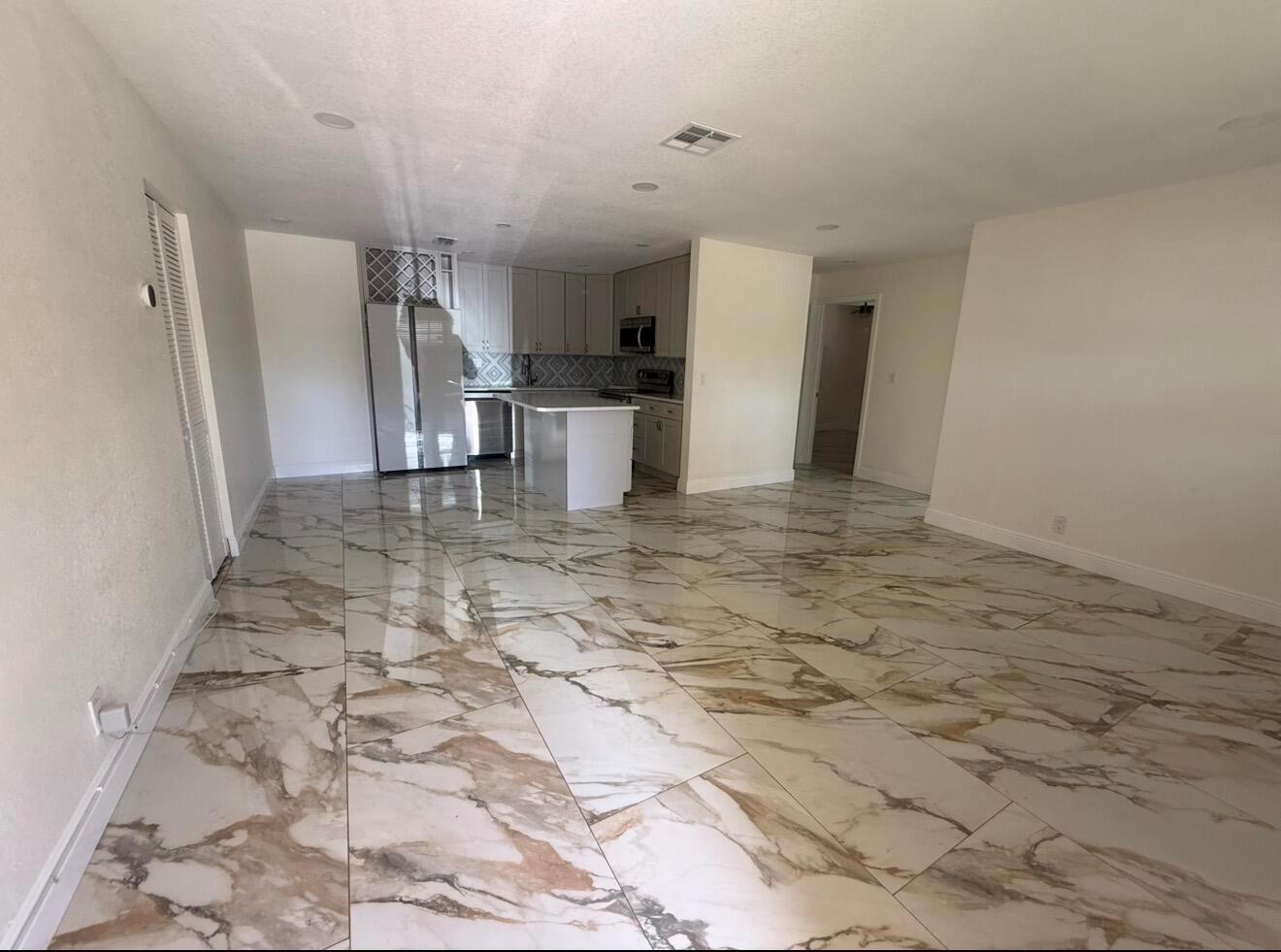 An open-concept kitchen and living area featuring large-format marble-patterned tile flooring — 2122 NE 1st Street, Boynton Beach FL 33435, BOYNTON BEACH, FL
