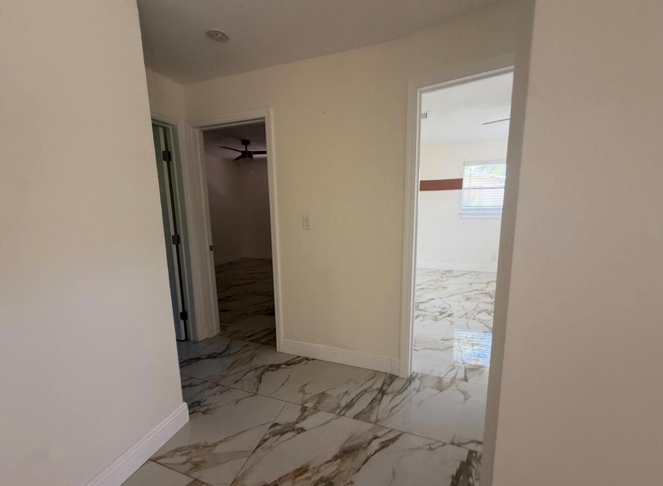 A hallway with white marble-patterned tile floors leads to two open doorways into separate rooms — 2122 NE 1st Street, Boynton Beach FL 33435, BOYNTON BEACH, FL