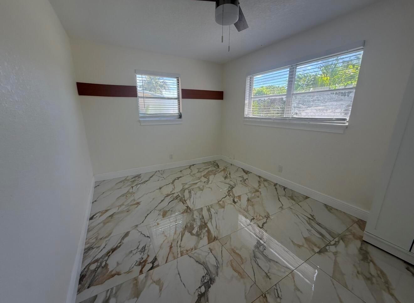 An empty bedroom features white walls with a dark accent stripe and marble-patterned tile flooring — 2122 NE 1st Street, Boynton Beach FL 33435, BOYNTON BEACH, FL
