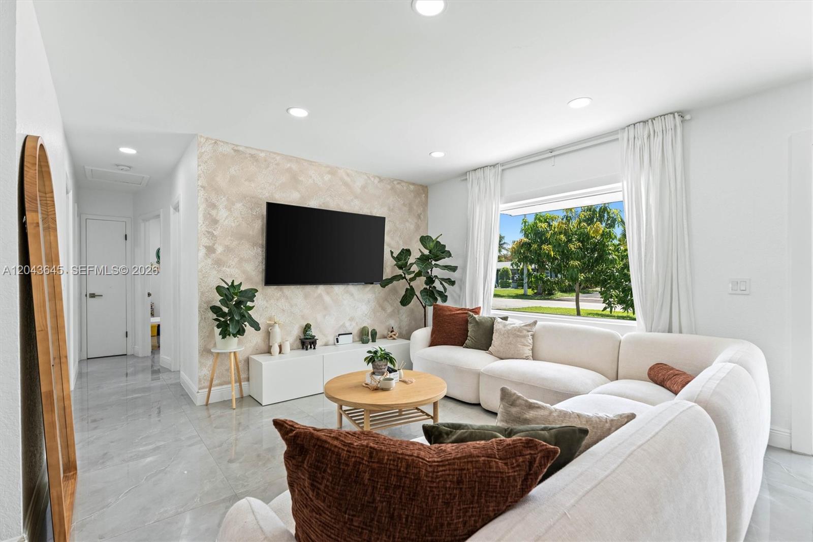 A living room features a textured accent wall, a white sectional sofa, and tile flooring — 1120 SW 7th Ave, Deerfield Beach FL 33441, DEERFIELD BEACH, FL