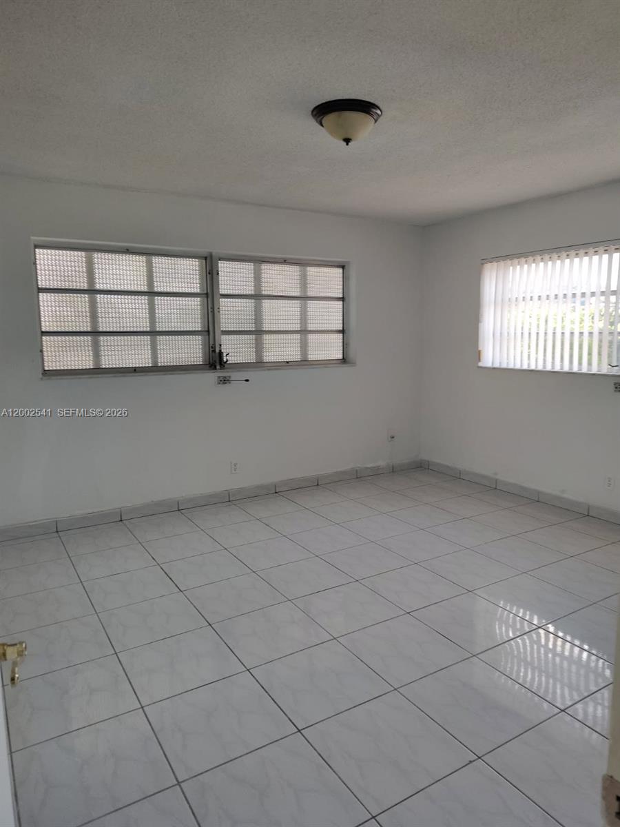 An empty room features white tile flooring, white walls, and two windows with blinds — 200 NE 12th Ave # 1C, Hallandale Beach FL 33009, HALLANDALE BEACH, FL