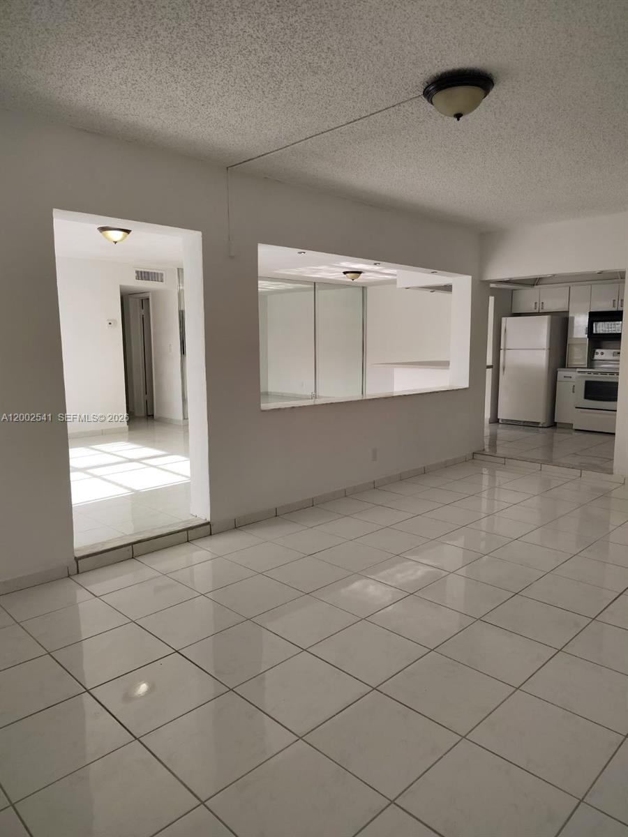A tiled living area features a pass-through window looking into a kitchen with white appliances — 200 NE 12th Ave # 1C, Hallandale Beach FL 33009, HALLANDALE BEACH, FL