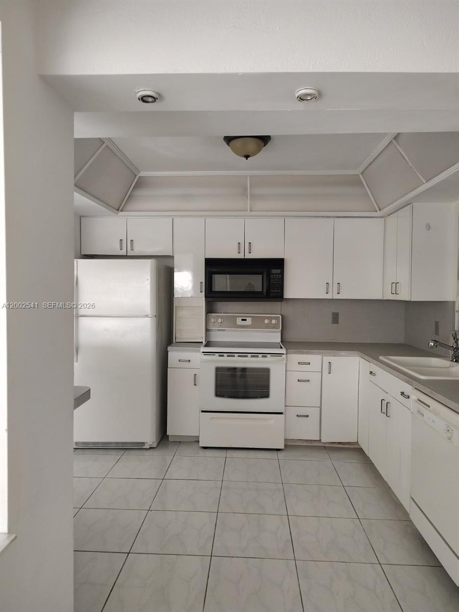 A kitchen features white cabinetry, white appliances, and light-colored tile flooring — 200 NE 12th Ave # 1C, Hallandale Beach FL 33009, HALLANDALE BEACH, FL