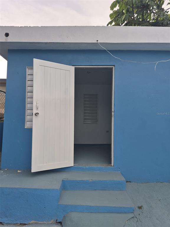 A blue exterior wall features a white door leading into a room with a window — 1 BARRIO MORA, ISABELA, PR