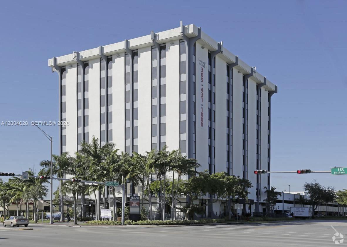 A multi-story office building with a white facade stands near a street intersection with palm trees — 12550 Biscayne Blvd UNIT 403, North Miami FL 33181, NORTH MIAMI, FL