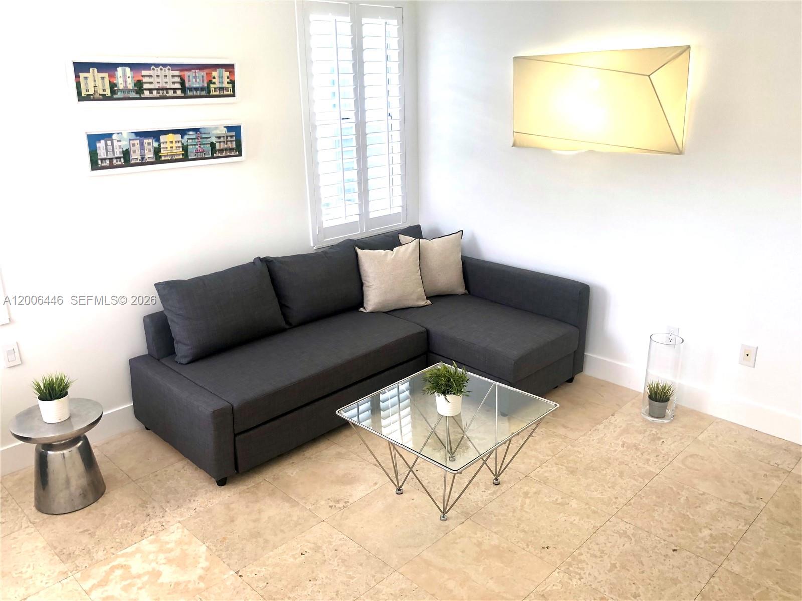 A living room features a dark gray sectional sofa, a glass coffee table, and wall art — 826 7th St # 3, Miami Beach FL 33139, MIAMI BEACH, FL