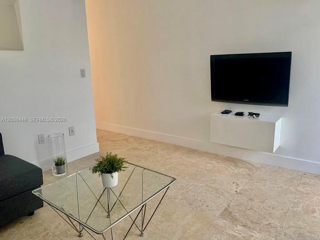 A living room features a wall-mounted television, a glass coffee table, and tile flooring — 826 7th St # 3, Miami Beach FL 33139, MIAMI BEACH, FL