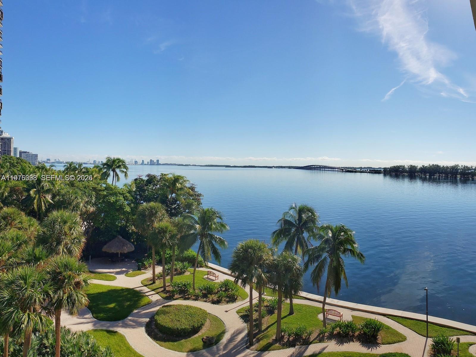 An elevated view of a waterfront park with palm trees, walkways, and a distant bridge — 2451 Brickell Ave # 18F, Miami FL 33129, MIAMI, FL