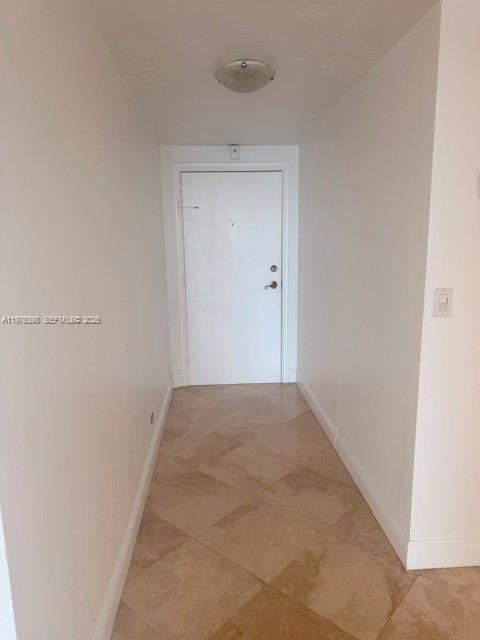 A hallway with light-colored tile flooring leads to a closed white door — 2451 Brickell Ave # 18F, Miami FL 33129, MIAMI, FL