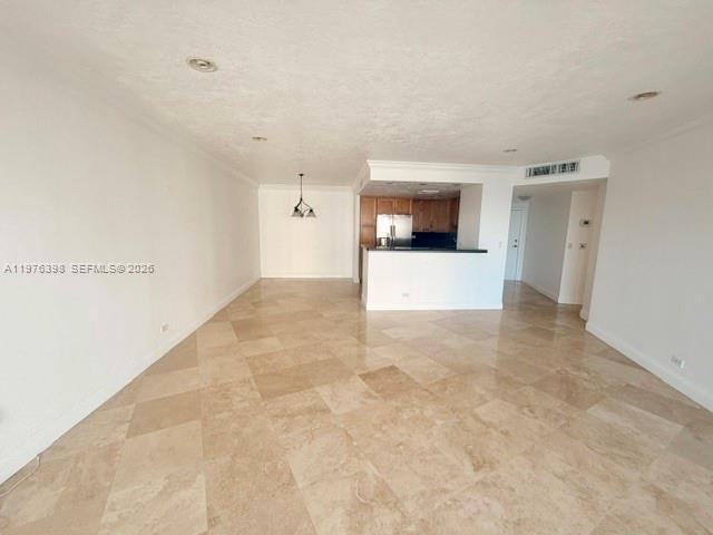 An open living area features light-colored tile flooring and a kitchen with wooden cabinets — 2451 Brickell Ave # 18F, Miami FL 33129, MIAMI, FL
