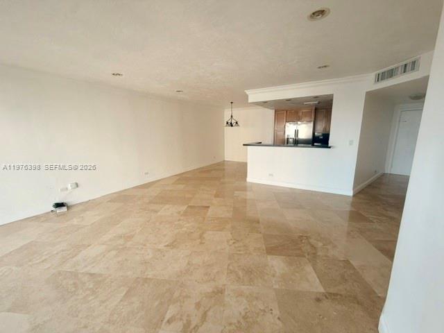 An open-concept living area features beige tile flooring and a kitchen with wooden cabinets — 2451 Brickell Ave # 18F, Miami FL 33129, MIAMI, FL