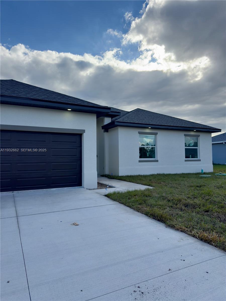 A single-story house with a beige stucco exterior, a two-car garage, and a concrete driveway — 748 748 CHESTNUT ST E, Lehigh Acres FL 33974, LEHIGH ACRES, FL
