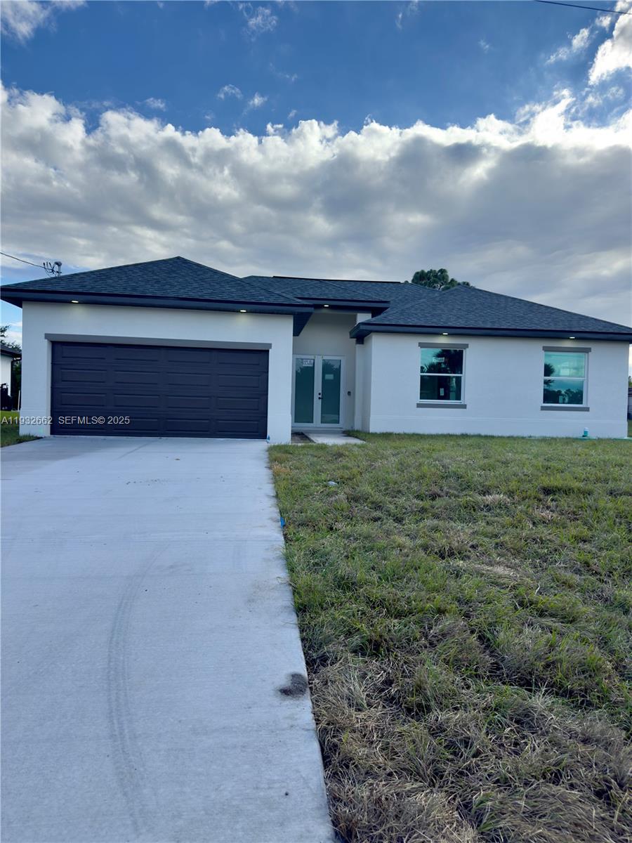 A single-story house with a beige stucco exterior, a dark roof, and a concrete driveway — 748 748 CHESTNUT ST E, Lehigh Acres FL 33974, LEHIGH ACRES, FL