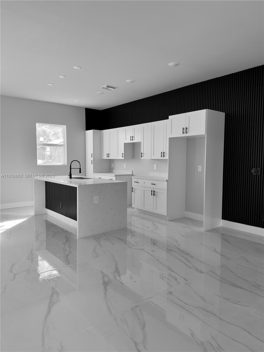 A concrete walkway leads to the double glass front doors of a modern stucco house — 748 748 CHESTNUT ST E, Lehigh Acres FL 33974, LEHIGH ACRES, FL
