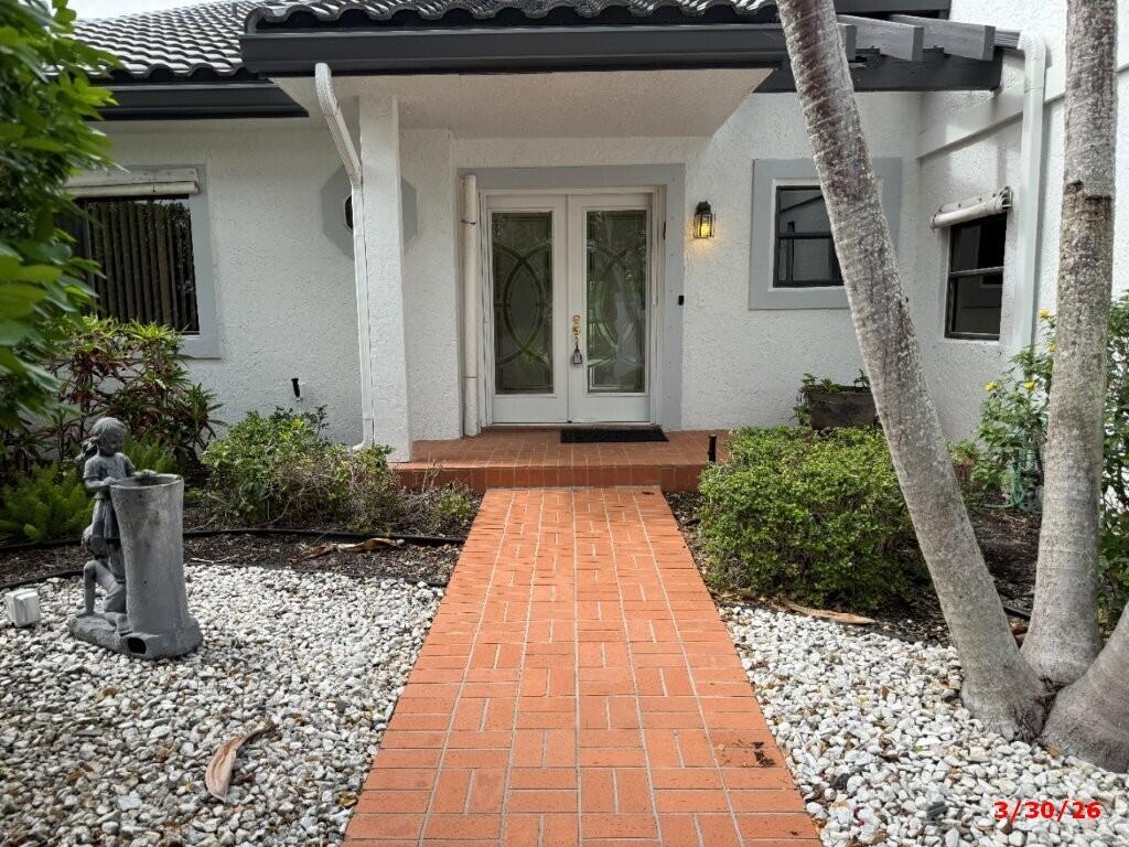 A brick walkway leads to the white double front doors of a single-story house — 9 Windsor Lane, Boynton Beach FL 33436, BOYNTON BEACH, FL