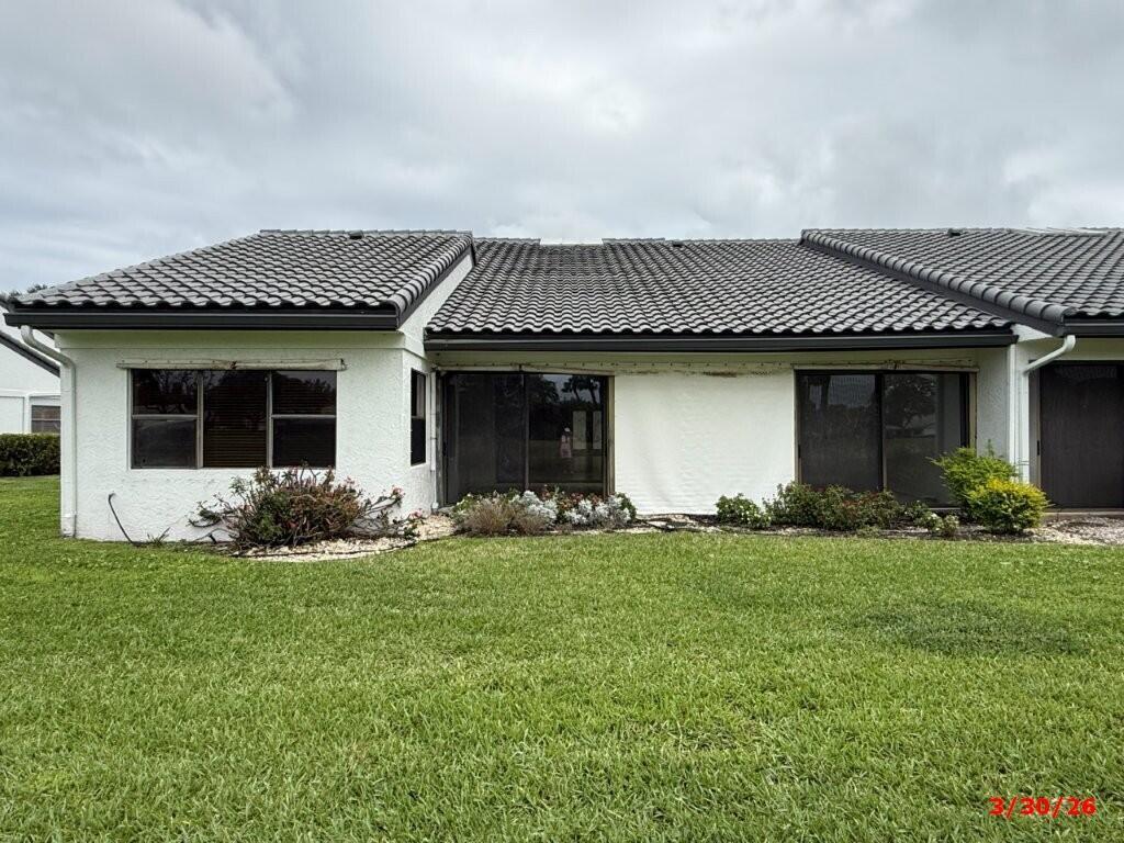 The exterior of a single-story home features a tiled roof, white stucco walls, and sliding doors — 9 Windsor Lane, Boynton Beach FL 33436, BOYNTON BEACH, FL
