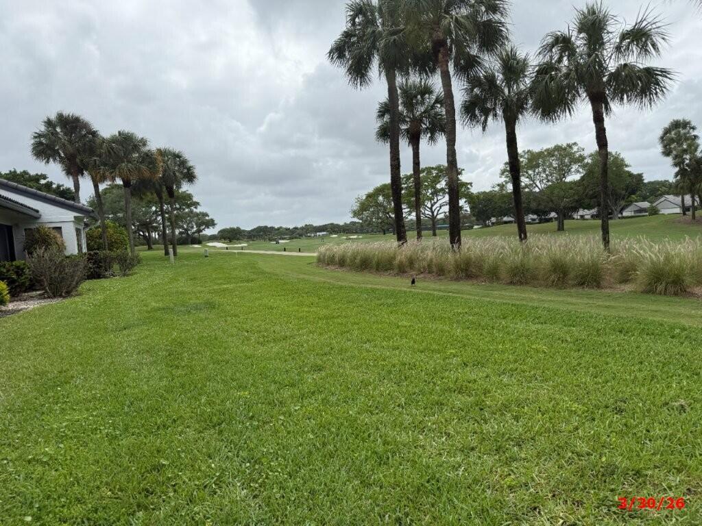 A grassy lawn leads toward a golf course lined with palm trees under a cloudy sky — 9 Windsor Lane, Boynton Beach FL 33436, BOYNTON BEACH, FL
