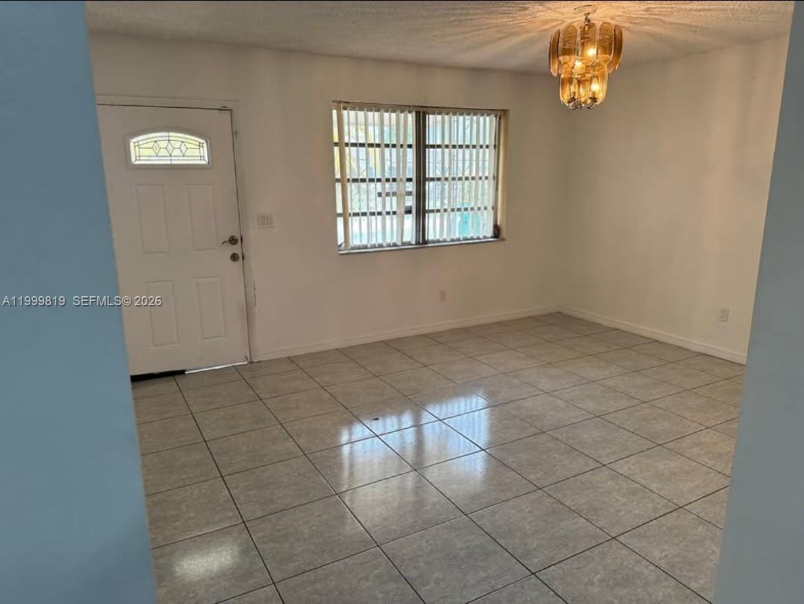 This room features light-colored floor tiles, white walls, a window with vertical blinds, and a chandelier — 9021 SW 30th Ter, Miami FL 33165, MIAMI, FL