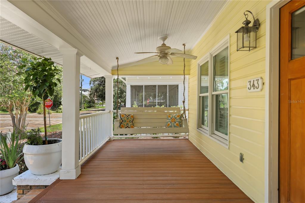 A covered front porch features a hanging swing, a ceiling fan, and yellow siding — 343 BROADWAY AVENUE, ORLANDO, FL