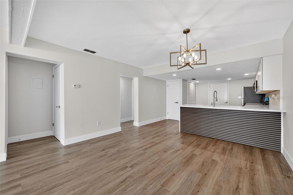 A living area with wood-look flooring leads to an open kitchen with a slatted breakfast bar — 9826 POCONO STREET, PORT RICHEY, FL