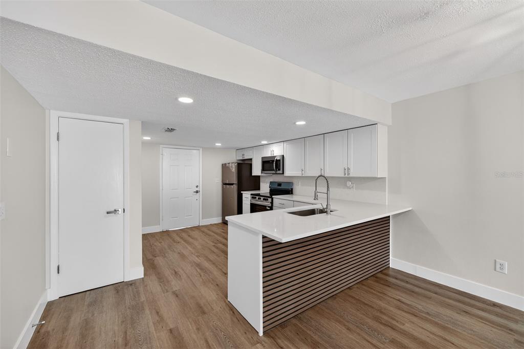 A kitchen features white cabinets, a slatted wood island, and light wood-look flooring — 9826 POCONO STREET, PORT RICHEY, FL