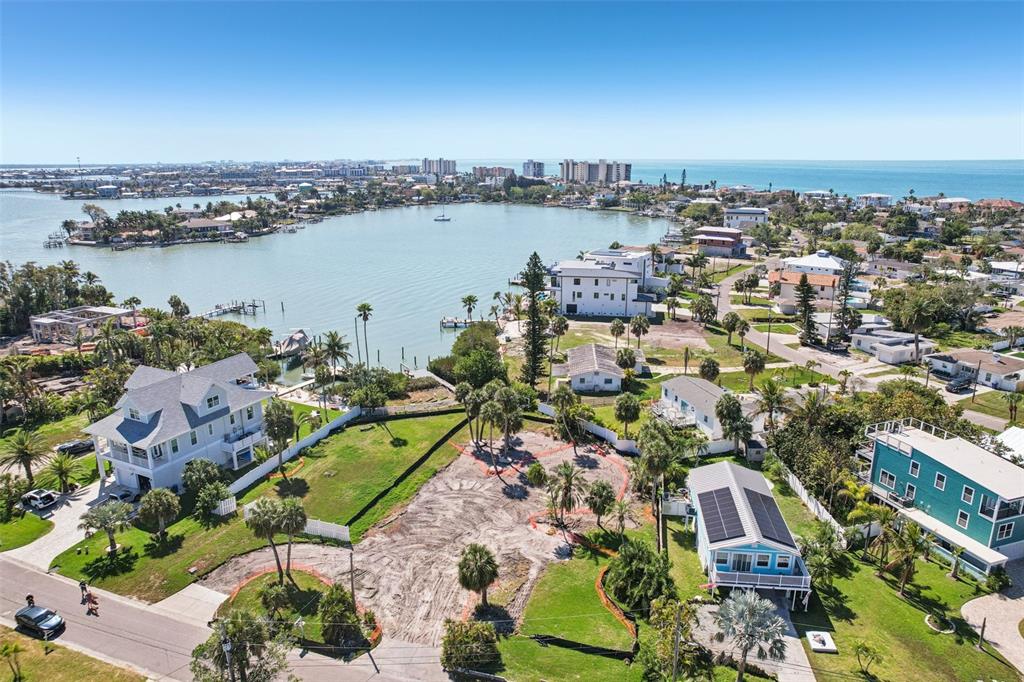 An aerial view shows a cleared waterfront lot situated between two houses near a bay — 15825 REDINGTON DRIVE, REDINGTON BEACH, FL