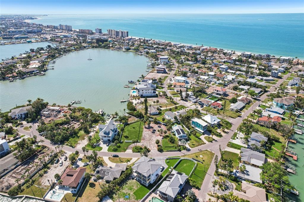 An aerial view shows a coastal neighborhood with houses surrounding a bay near the ocean — 15825 REDINGTON DRIVE, REDINGTON BEACH, FL