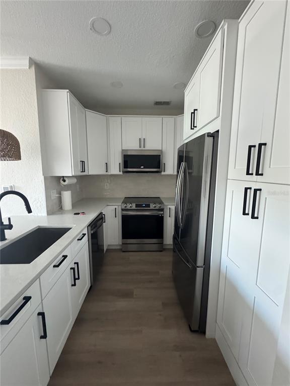 A modern kitchen features white cabinets, stainless steel appliances, and a dark sink — 5000 CULBREATH KEY WAY UNIT 8-122, TAMPA, FL