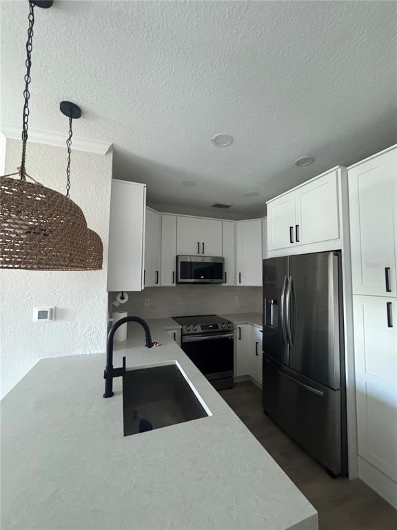 A modern kitchen features white cabinets, stainless steel appliances, and a quartz-topped island with sink — 5000 CULBREATH KEY WAY UNIT 8-122, TAMPA, FL