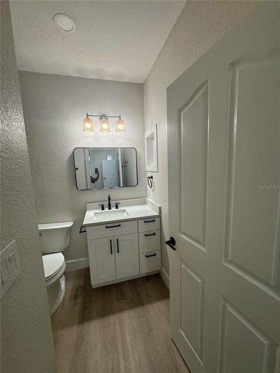 A bathroom features a white vanity, a rectangular mirror, a toilet, and light wood flooring — 5000 CULBREATH KEY WAY UNIT 8-122, TAMPA, FL