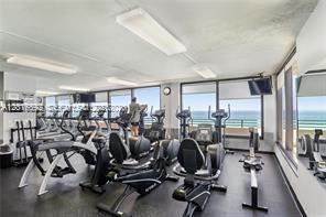 A gym with exercise equipment and large windows overlooking the ocean — 5555 Collins Ave # 14U, Miami Beach FL 33140, MIAMI BEACH, FL
