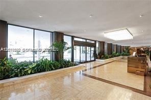 A bright lobby features large windows, potted plants, and a polished tile floor — 5555 Collins Ave # 14U, Miami Beach FL 33140, MIAMI BEACH, FL