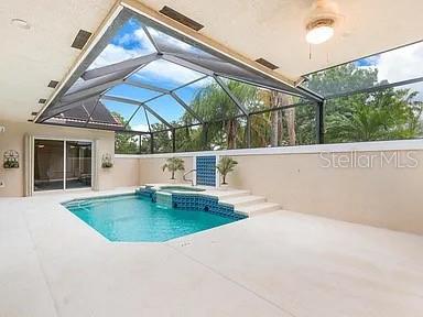 A screened-in patio features a swimming pool with an integrated spa and light-colored concrete decking — 910 SW MUNJACK CIRCLE, PORT ST LUCIE, FL