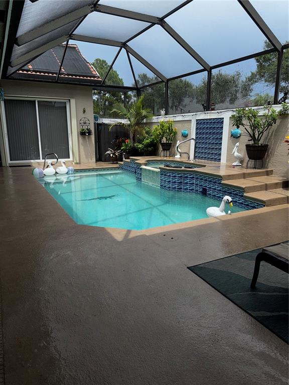 A screened-in patio features a swimming pool with a raised spa and blue tile accents — 910 SW MUNJACK CIRCLE, PORT ST LUCIE, FL