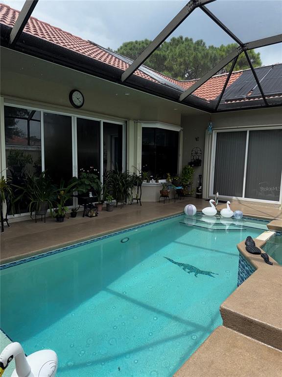 A screened-in swimming pool patio features a tiled deck, potted plants, and sliding glass doors — 910 SW MUNJACK CIRCLE, PORT ST LUCIE, FL
