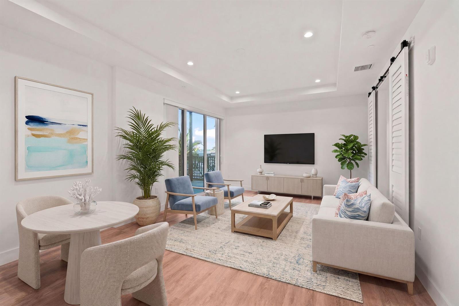 This living and dining area features light wood floors, a neutral sofa, and two blue chairs — 41 SW Seminole Street # 204, Stuart FL 34994, STUART, FL