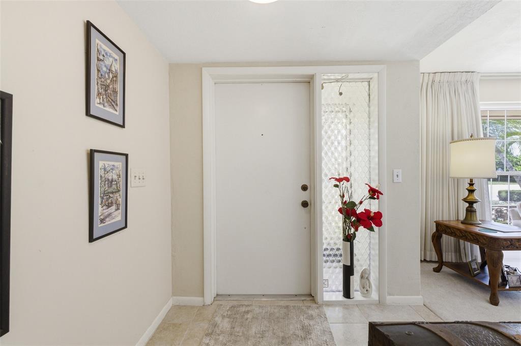 An entryway features a white front door, a glass sidelight, and two framed wall pictures — 1335 WHISKEY CREEK DRIVE, FORT MYERS, FL