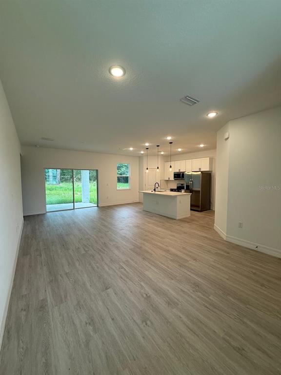 An open-concept kitchen and living area features light wood-look flooring and a sliding glass door — 9481 N STAFFORD DRIVE, CITRUS SPRINGS, FL