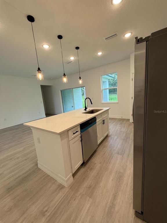 A kitchen island with a sink and pendant lighting sits in an open-concept room — 9481 N STAFFORD DRIVE, CITRUS SPRINGS, FL