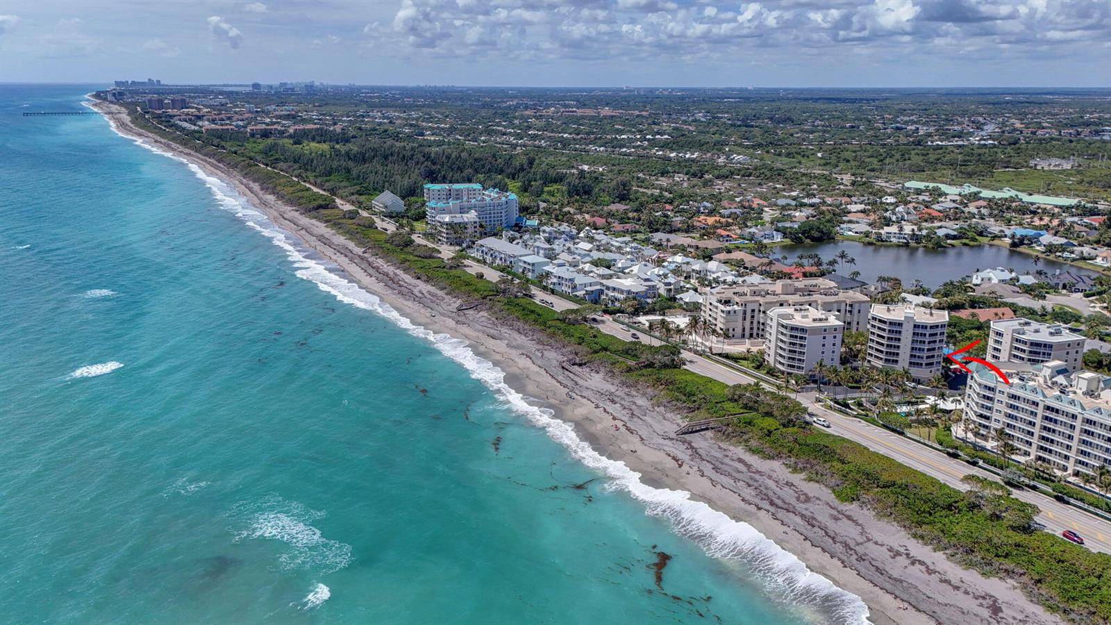 An aerial view shows beachfront condominiums along a coastline with a red arrow pointing down — 1660 S Highway A1a (plus Deeded Sep. Guest Quarters) # 222, Jupiter FL 33477, JUPITER, FL
