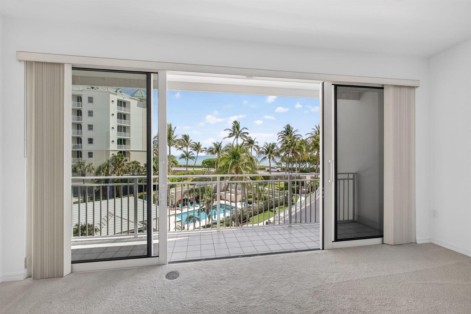 A carpeted room features large sliding glass doors opening to a balcony with ocean views — 1660 S Highway A1a (plus Deeded Sep. Guest Quarters) # 222, Jupiter FL 33477, JUPITER, FL